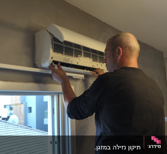 אדם מתקין מזגן על קיר בחדר